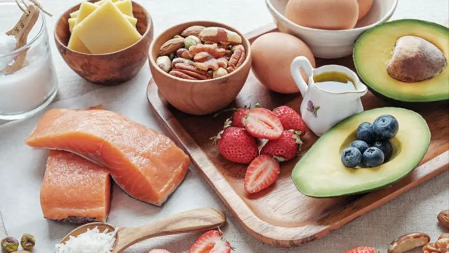 Salmón, huevos, aguacate, frutos rojos y frutos secos sobre la mesa