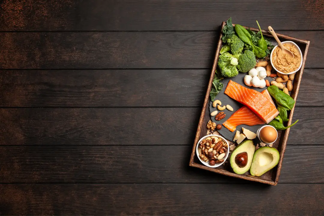 Bandeja con salmón, aguacate, huevos, verdura y frutos secos sobre una mesa de madera