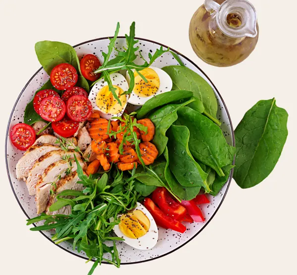 Plato de keto mediterránea con huevo, pollo, tomate, aguacate y hojas verdes